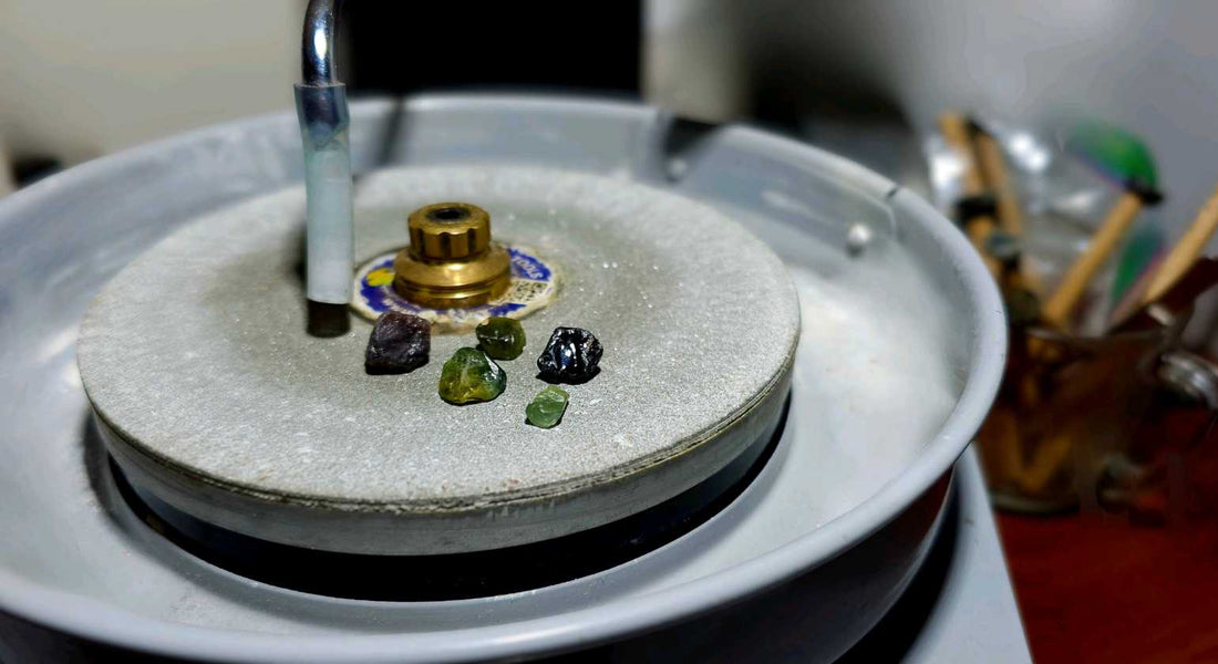 Rough Australian Sapphires and a zircon on a faceting machine in a gem-cutting workspace, showing the early stages of lapidary work.